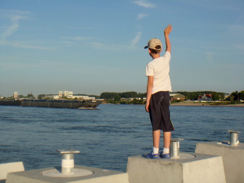 Boy waving goodbye to a ship