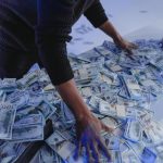 Man standing over pile of cash