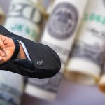 Man looking at watch with cash in background