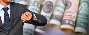 Man looking at watch with cash in background